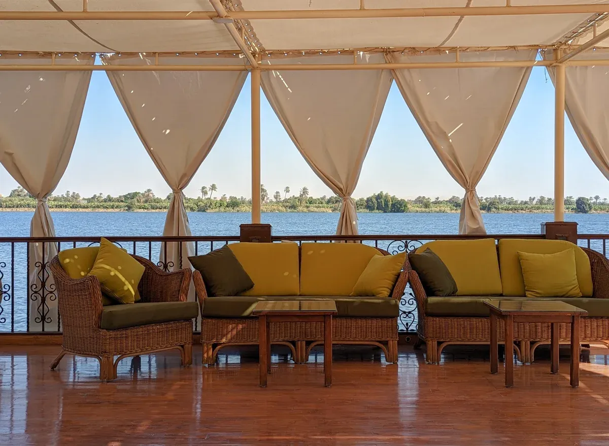 The shaded lounge deck of a dahabiya looking over the river on a Nile river cruise